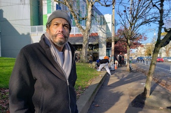 caption: Carlos Faas gathers food in the U District before finding a warm place to sleep on Tuesday, December 3, 2024.