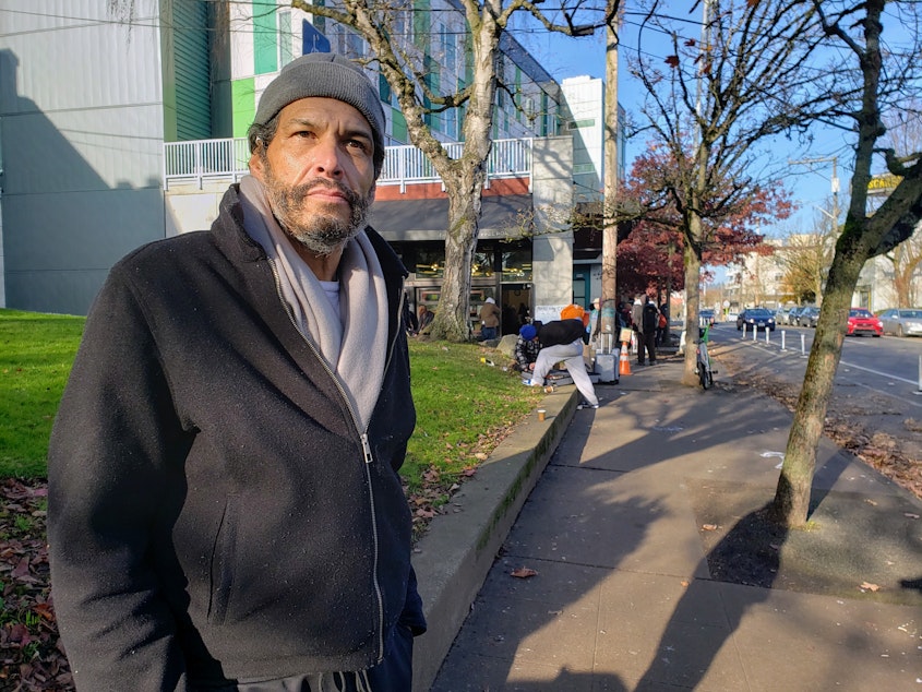 caption: Carlos Faas gathers food in the U District before finding a warm place to sleep on Tuesday, December 3, 2024.