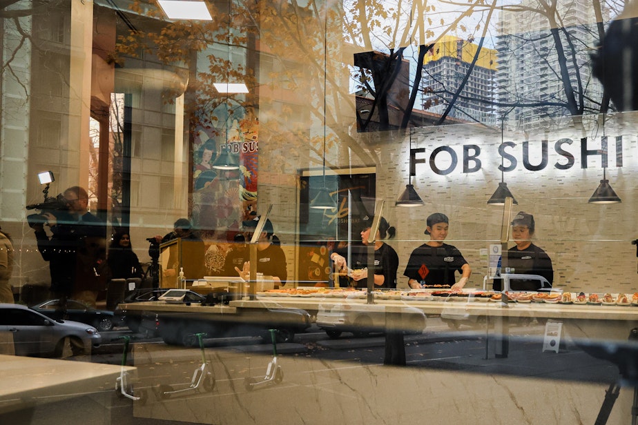 caption: Workers at FOB Sushi Bar in Seattle's Belltown neighborhood prepare the bar for its reopening on Dec. 3, 2024.