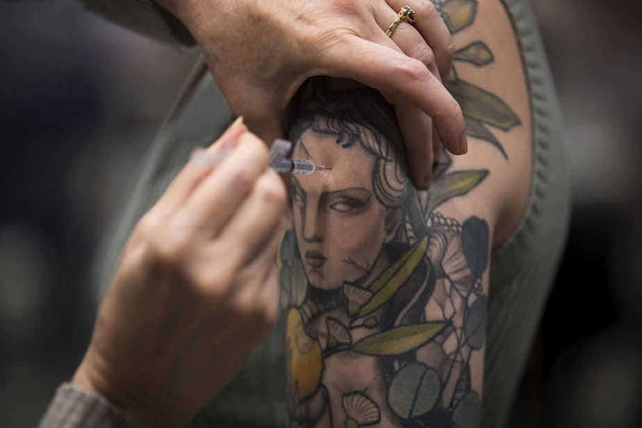 caption: Lauren Alexander is vaccinated against Covid-19 on Thursday, April 15, 2021, at the Lumen Field Event Center in Seattle.