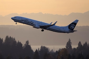 caption: A jet departs from Seattle-Tacoma International Airport in 2018.