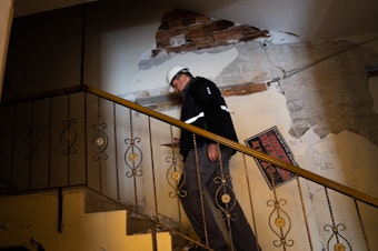 caption: Yasin Pinarbasi walks into a building he inspected that suffered some earthquake damage, west of Antakya, Turkey.