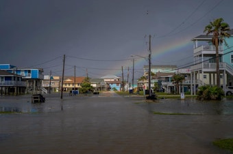 caption: A rainbow appears behind a flooded neighborhood in Jamaica Beach, Texas, on Thursday.
