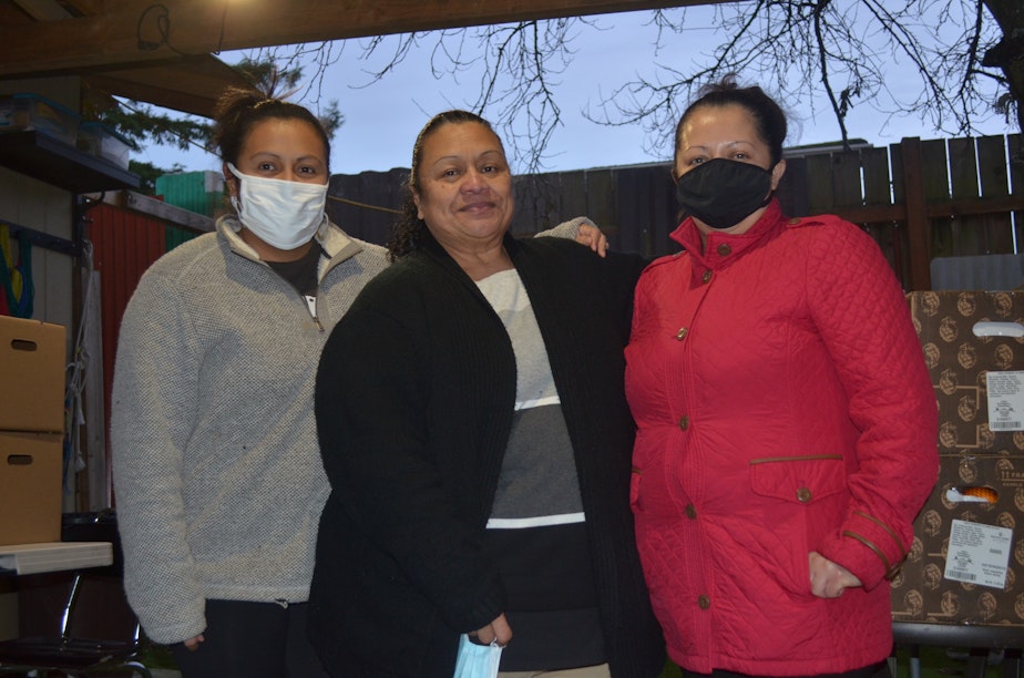 caption: Isabel Quijano (center) is a community health worker who helps people find Covid vaccine appointments.