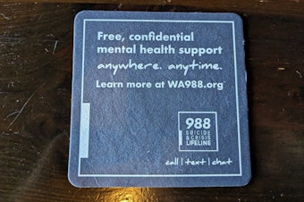 caption: A coaster at a pub in Seattle advertises the 988 hotline in August 2024.