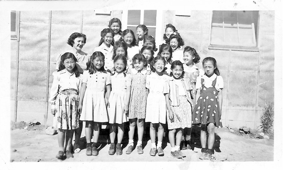 caption: Alice Hikido (front row, third from the right) stands at the Minidoka, Idaho, prison camp in 1943. She wears a dress gifted to her by friends in Juneau, Alaska before she and her family were forcibly removed.