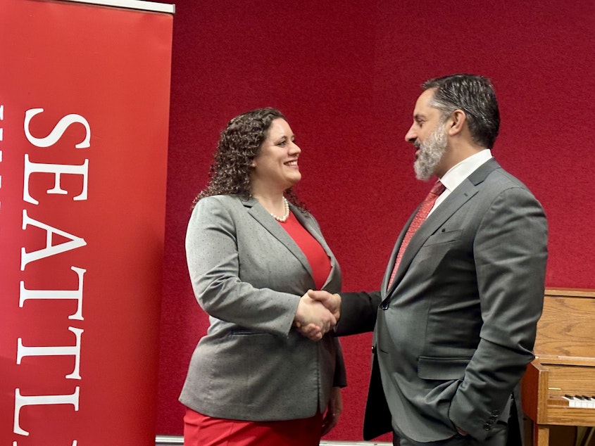 caption: Emily Parkhurst, Cornish College of the Arts' interim president, and Seattle University President Eduardo Peñalver shake hands as they pose for a photo December 5, 2024. The two private colleges announced their intent to merge.