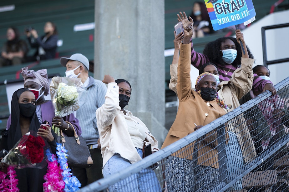 caption: Betty Ayneta, center, and Genet Tesfamariam cheer for their cousin and nephew, graduate Haben Yohannes, as the Cleveland Stem High School class of 2021 walks into Memorial Stadium ahead of the commencement ceremony on Tuesday, June 15, 2021, in Seattle.