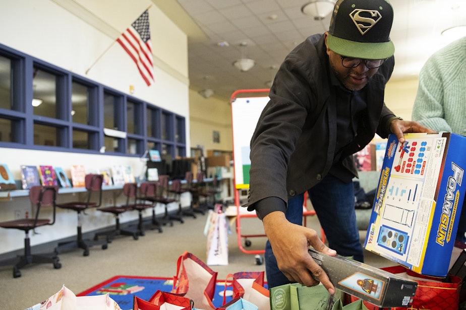 caption: Rogers Greene, a family support worker at Dunlap Elementary School, sorts gifts for students on Friday, December 20, 2024, at Dunlap Elementary School in Seattle.