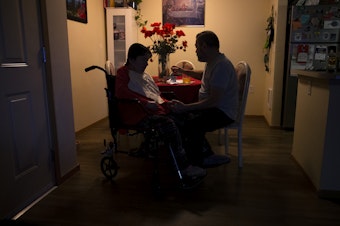 caption: Omar, right, feeds his wife Marta, left, at their apartment on Tuesday, September 26, 2023, in Everett.