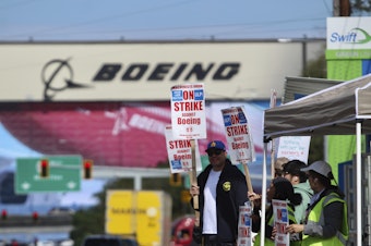 caption: Union machinists and supporters wave picket signs in Everett, Washington, Thursday, Sept. 19, 2024, near a Boeing factory.