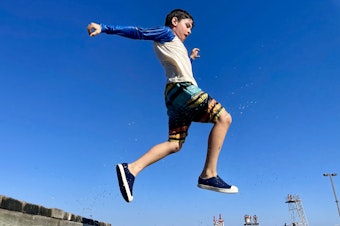 caption: Pablo, 9, jumps into the waters of Lake Washington in September. 