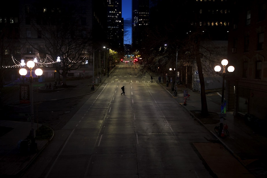 caption: A pedestrian crosses an empty 4th Avenue on Wednesday, March 25, 2020, in Seattle.