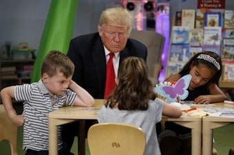 caption: Donald Trump visits with a group of children during his first term as president Friday, Aug. 24, 2018, in Columbus, Ohio. Trump's reelection has raised questions about education funding in Washington state and across the country.