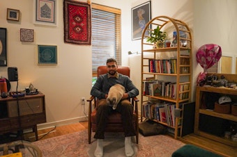 caption: Pasha the cat, was one of the things Aysenur Eygi loved the most. To the right of Hamid Ali, above, the bookcase was an art creation of Eygi. 