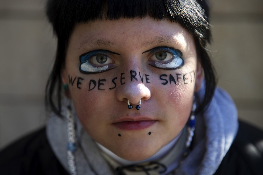 caption: E.O Franklin-Bihary was a sophomore at Ingraham High School when a student was shot and killed in the school. They're portrayed with the words "we deserve safety" painted across their face during a student walkout to protest gun violence in schools on Monday, Nov. 14, 2022, at Seattle City Hall. 