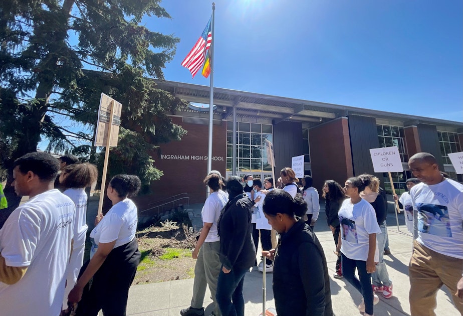 caption: On April 26, 2022, protesters walked past Ingraham High School, where 17-year-old Ebenezer Haile was killed. Behind them, Haile's mother, Tsedale Woldemariam, and his younger brother hugged. It was the first time they'd been back at the school since his death.