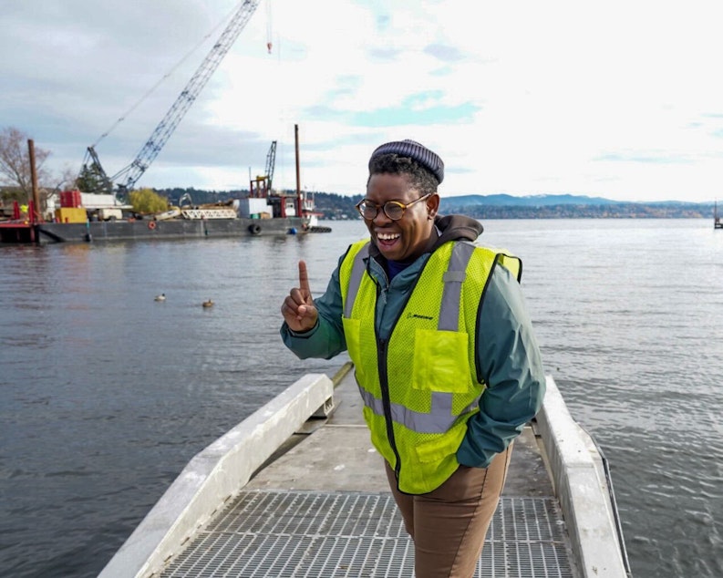 caption: Ashley Townes stands at the edge of Lake Washington where logs are being arranged in the water to help promote aquatic plant growth, enhance water quality, and provide habitat for animals.