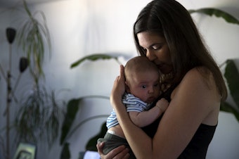 caption: Marina Heppenstall holds her 2-month-old son Arlo, on Tuesday, July 16, 2024, at their home on Bainbridge Island. 