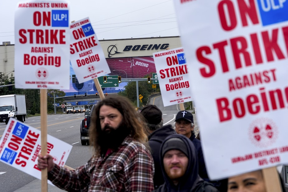 caption: Boeing workers wave picket signs to passing drivers as they strike after union members voted to reject a contract offer Sunday, Sept. 15, 2024, near the company's factory in Everett, Wash. 