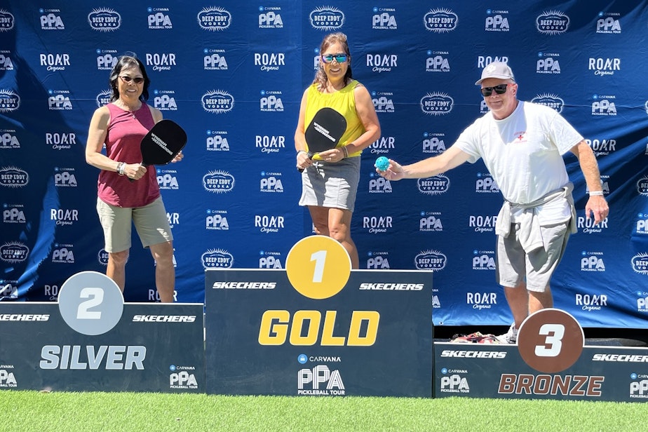 caption: Pickleball amateurs fool around on the winner's stand before they play in the Seattle Open pickleball tournament.