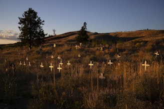 caption: Unmarked graves are shown behind St. Mary’s Catholic Mission on Thursday, July 20, 2017, in Omak. 