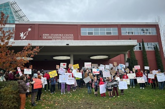 caption: Parents and students hold signs outside a Seattle Public Schools board meeting on Tuesday, November 19, 2024.