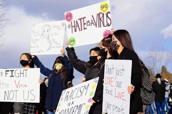 caption: Community members show signs in support of the AAPI community during a vigil for the victims of the Atlanta shooting in March