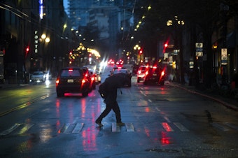 caption: A pedestrian crosses First Avenue with an umbrella on Tuesday, Dec. 5, 2023, in Seattle.