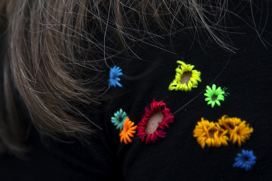 caption: Keri Bergere, a survivor of a recent cougar attack, wears the shirt that she was wearing during the attack with the holes and tears colorfully stitched, on Wednesday, March 13, 2024, at Log Boom Park in Kenmore. 