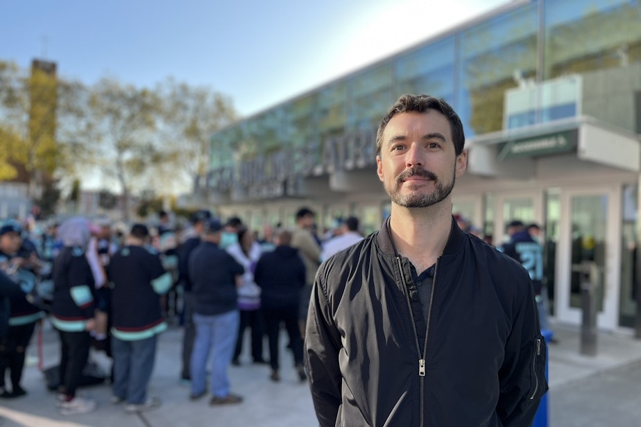 caption: Colin López teaches sports economics at Seattle University. He stands in front of Climate Pledge Arena as fans line up for a game in the fall of 2024.