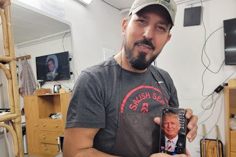 caption: Ibrahim Aljalal poses with pictures of Donald Trump on his phone inside his barbershop on Sunday, November 17, 2024.