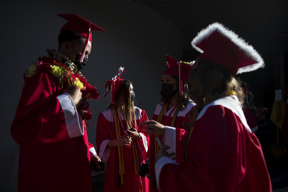 caption: Cleveland Stem High School seniors from left, Makana Haynes, Megan Louie, Isabella Caldejon and Aaliyah Caldejon talk before the start of the in-person commencement ceremony on Tuesday, June 15, 2021, at Memorial Stadium in Seattle.