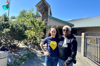 caption: Joy Anderson and her daughter Olivia Wilkinson stand in front of the former Cooper Elementary, which shuttered in 2009, during Seattle's last wave of school closures. The school now houses Pathfinder K-8.