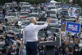 caption: Then presidential candidate Joe Biden waves to supporters as he finishes speaking during a drive-in campaign rally in Georgia in 2020.