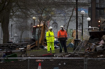 caption: Parks and Recreation employees clear tents, belongings and debris from the former encampment of unhoused community members following a sweep on Friday, December 18, 2020, at Cal Anderson Park in Seattle. 