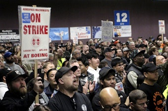 caption: Boeing machinists, labor allies and elected officials rally in Seattle at their union hall on Tuesday, Oct. 15, 2024.