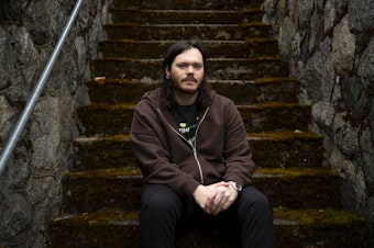 caption: Keenan Calhoun, a 29-year-old grocery clerk at the Lake City Fred Meyer is portrayed on Thursday, April 20, 2023, outside of his home in Seattle. 