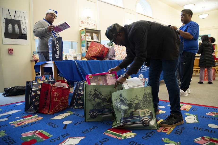 caption: Rogers Greene, a family support worker at Dunlap Elementary School, sorts gifts for students on Friday, December 20, 2024, at Dunlap Elementary School in Seattle.