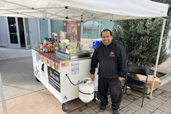 caption: Even though Marcus Arellano serves cold foods, he need the gas tank to heat up water for his hand washing station on the other side of his food cart. 