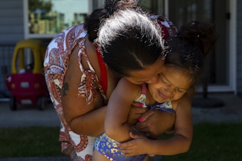 caption: Tynikki Arnold kisses her 5-year-old daughter Vay’s cheek while playing outside of their apartment on Friday, July 15, 2022. 