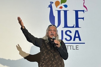 caption: Sanjoy K. Roy, the managing director of Teamwork Arts, welcomes an audience to the first Jaipur Literature Festival in Seattle at the Seattle Asian Art Museum on Sept. 20, 2024.