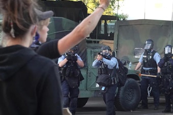 caption: Police prepare to open fire with tear gas and nonlethal rounds on a group of demonstrators protesting the death of George Floyd on May 29, 2020, in Minneapolis, Minn.
