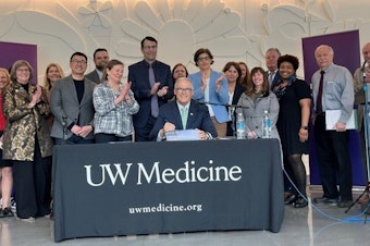 caption: Washington Gov. Jay Inslee (center) pictured at what's likely to be the last bill-signing of his time in office.