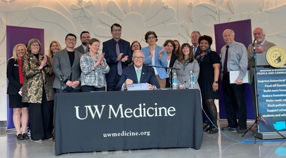 caption: Washington Gov. Jay Inslee (center) pictured at what's likely to be the last bill-signing of his time in office.