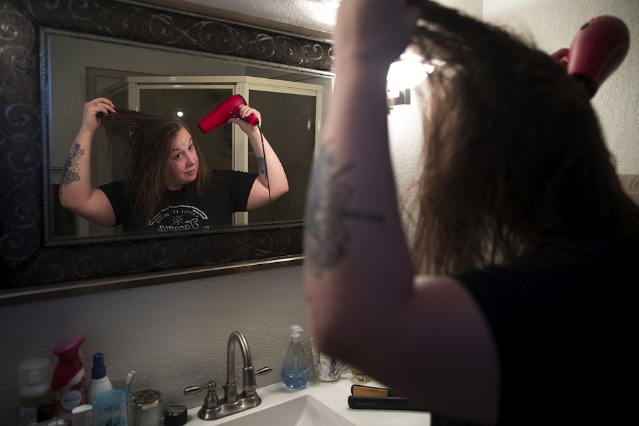 caption: Kara Peters blow dries her hair while getting ready for work on Wednesday, January 22, 2020, at her home in Tacoma. Peters commutes by bus from Tacoma to her job at the Seattle Public Central Library.