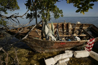 caption: A wooden migrant boat lies grounded on a reef alongside mangroves, at Harry Harris Park in Tavernier, Fla., last year. The U.S. Coast Guard says that since October, has it intercepted and returned about <a href=_.html data-key="28">130 migrants to Haiti</a>.