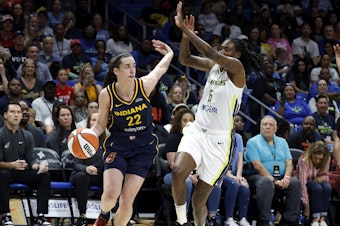 caption: Indiana Fever guard Caitlin Clark (22) drives past Dallas Wings forward Natasha Howard (6) during their WNBA basketball game in Arlington, Texas, on Friday.