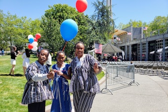 caption: Clare Adabrer and her two kids at Seattle Center during the naturalization ceremony on Thursday, July 4, 2024.