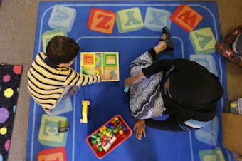 caption: Declan Hart, 4, left, and teacher-in-training Deassi Usman, right, play with shape blocks during a Pre-Kindergarten class at the Community Day Center for Children, during class Tuesday, Oct. 21, 2014, in Seattle.